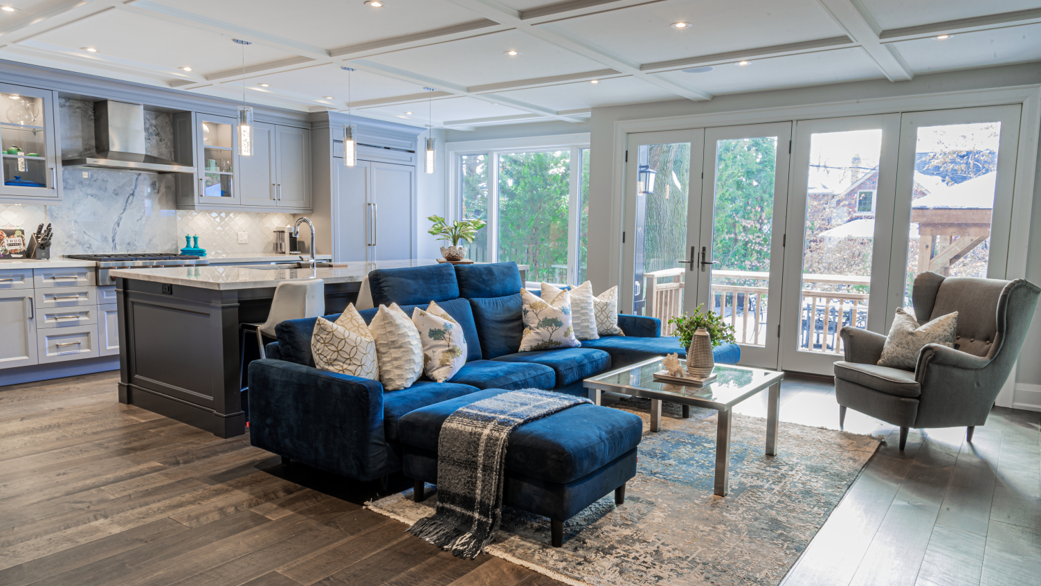 large, transitional open concept kitchen and living room with blue sofa and custom pillows